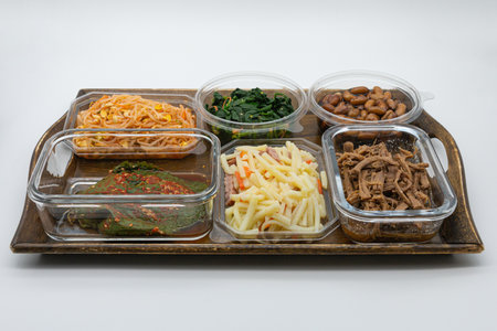 Korean food in plastic containers on a wooden tray, white backgroundの写真素材