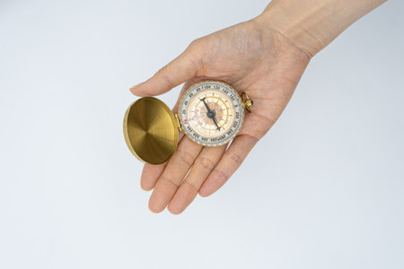 Female hand holding a compass on a white background with copy space.の写真素材