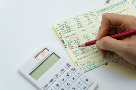 calculator and financial statement with red pen on white background.の写真素材