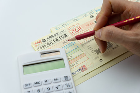 Close up of a man's hand using a calculator and a passportの写真素材