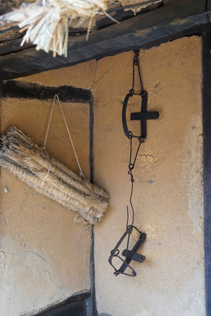 Hanging black cross and rope on the wall of an old houseの写真素材