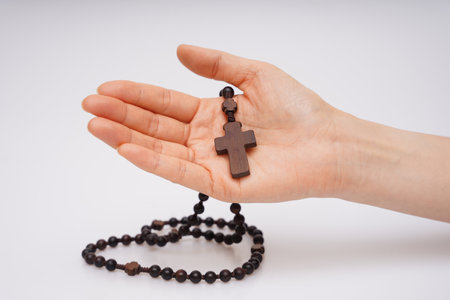 Wooden cross and rosary in hand on a white backgroundの写真素材