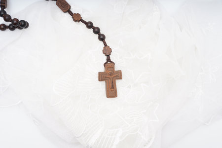 Wooden rosary with a cross on a white background.の写真素材