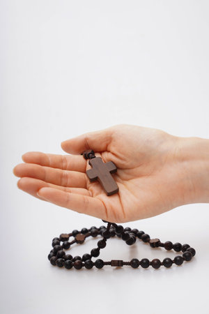 wooden rosary in the hands of a woman on a white backgroundの写真素材