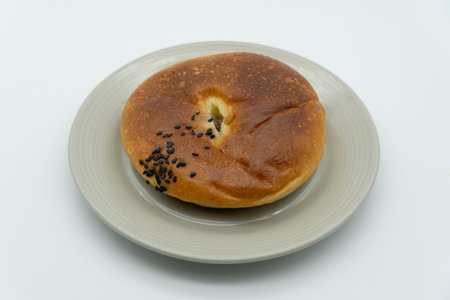 Bagel with poppy seeds on a plate on a white backgroundの写真素材