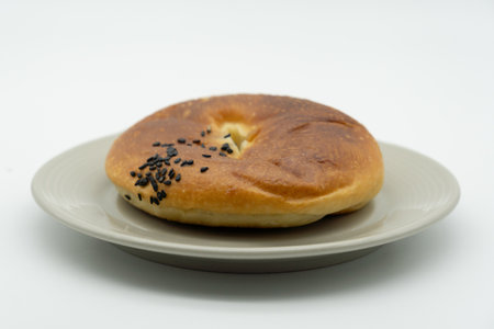 Bagel with sesame seeds on a plate on white backgroundの写真素材