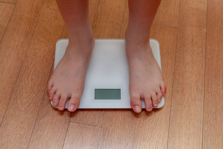 Woman's feet on weight scale on wooden floor. Dieting conceptの写真素材
