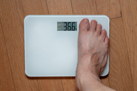 Close up of a man's foot on a weight scale with digital displayの写真素材