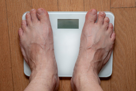 Close up of a man's feet standing on a weight scale.の写真素材