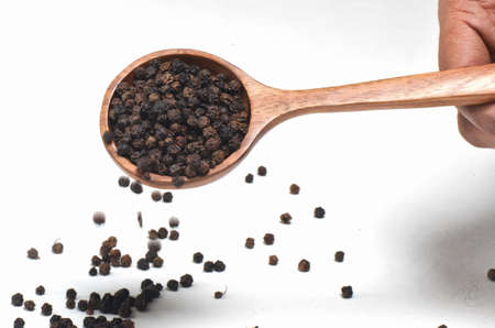Black pepper spices in wooden spoon