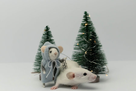 White little rat among beautiful holiday trees in the forest. A toy in the form of a plush ratの写真素材