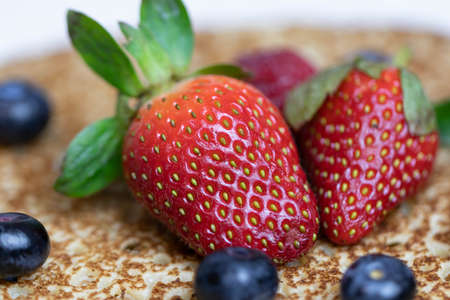 Ripe juicy strawberries and blueberries lie on a delicious pancake. Russian cuisine national dish...
