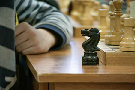 Playing wooden chess on a chessboard. Tactics and strategy. Black and white shapes.