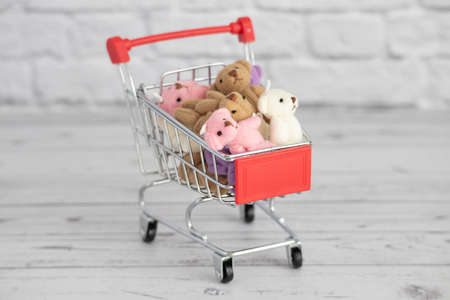 Many colorful toys teddy bears lie in the grocery cart. Shopping in the market. Buying gifts for birthdays and holidays.の写真素材