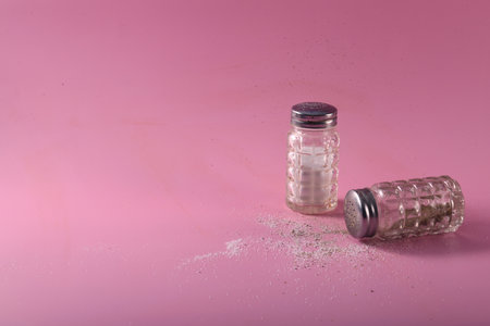 Salt and pepper shakers on pink surface. Horizontal photo with copy space to the left.の写真素材