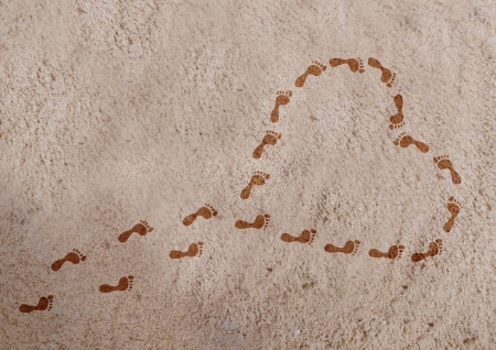 Heart shape with footprints on the sand の写真素材