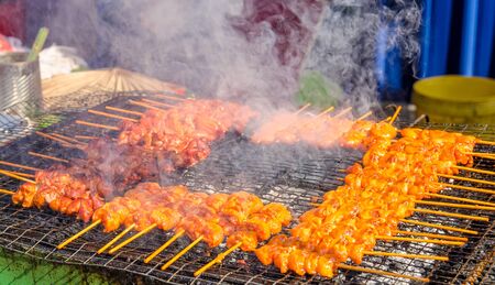 Tasty satay chicken cooking on a hot charcoal grill in Ramadan Bazaar during the holy month of Ramadan.の写真素材