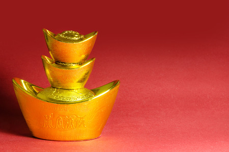 Chinese New Year gold ingots decorations on red background. (English translation for foreign text means blessing).の写真素材