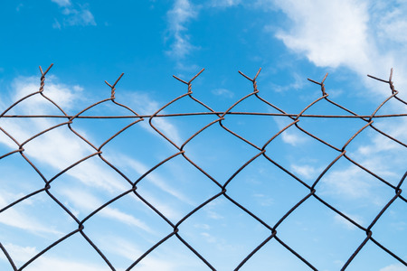 Old rusty metal fencing with blue sky backgroundの写真素材