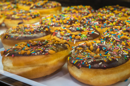 Close-up of the donuts with colorful sprinkles arranged on tray at bakery shop.の写真素材
