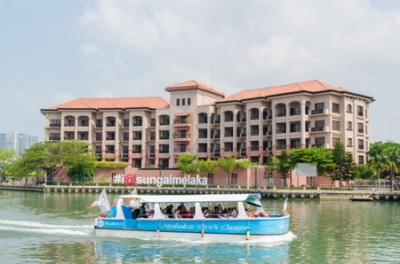 Malacca, Malaysia - April 21, 2019:  Riverside scenery of a cruise full of passengers crossing by the Malacca River. It has been listed as UNESCO World Heritage Site since 7/7/2008.のeditorial素材