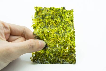 Close-up view of the hand holding a piece of roasted seaweed sheet isolated on white background.
