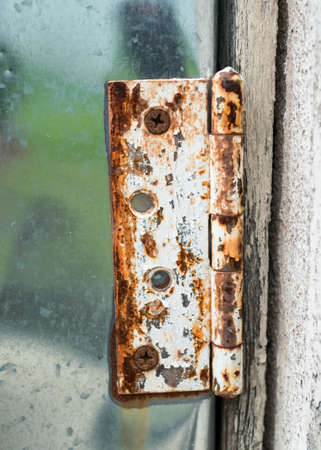 Close-up view of an old rusty hinge on aluminium door.の写真素材