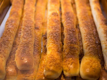 Close-up view of the chesse stick breads on a tray and selling in the bakery shop.