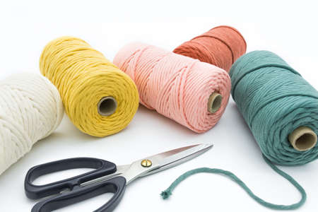 Close-up view of the colorful single strand cotton cords and scissor for macrame DIY handcraft.