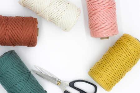 Close-up view of the colorful single strand cotton cords and scissor for macrame DIY handcraft...