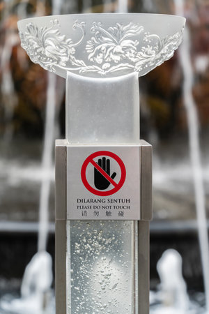 Close-up view of the "Please do not touch" sign with the water fountain as background.の写真素材