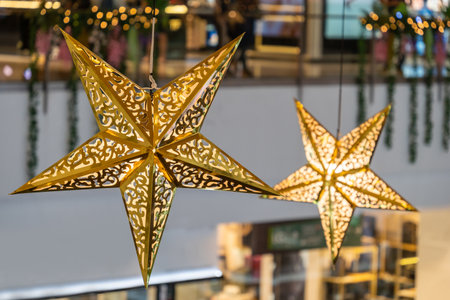 Close-up view of the glowing stars decoration hanging in the shopping mall during celebration Merry...