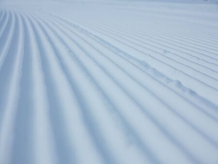 Snow velvet close up on ski slope. Prepared ski and snowboard track with trace of snow groomer on snowの写真素材