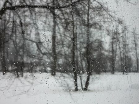 Raindrops on window with the picturesque winter landscapeの写真素材