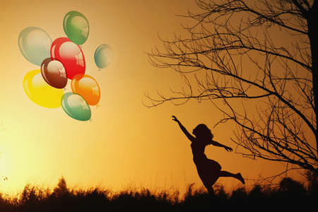  woman holding balloons and looking at sunの写真素材