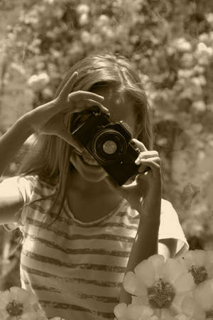 Happy girl in garden taking picturesの写真素材