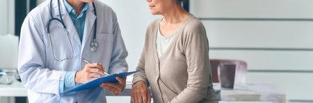 Doctor and patient discussing something while sitting at the table. Medicine and health care concept.の素材