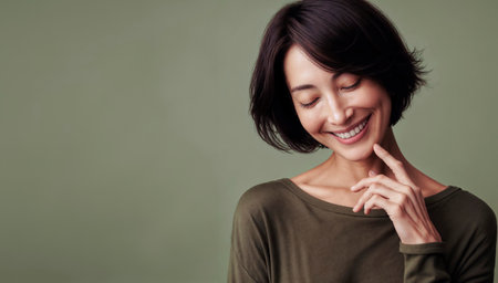 Portrait of a beautiful young asian woman smiling against green backgroundの素材
