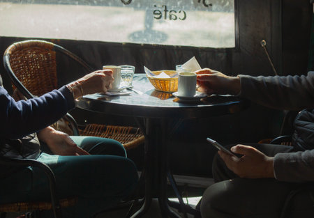 Coffee shop in Paris, France. Couple drinking coffee and using smartphone