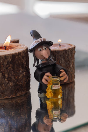 Witch doll with a bottle of honey and candles on the table