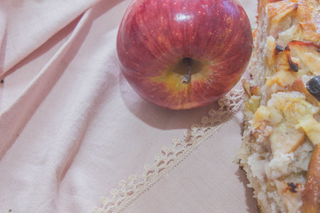 Apple pie on a pink cloth with a red apple in the backgroundの写真素材