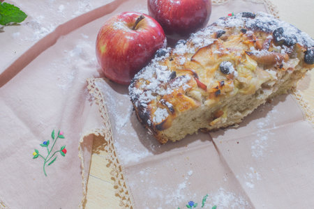 Apple pie with raisins and powdered sugar on a wooden tableの写真素材