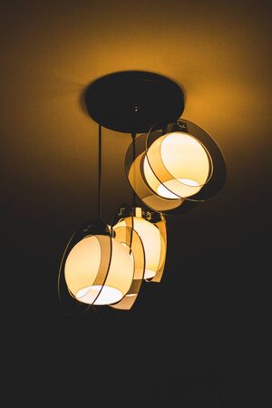 Chandelier slightly illuminating the ceiling of a roomの写真素材