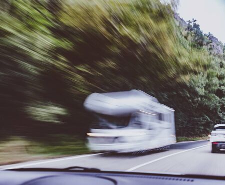 Motion blur of caravan passing on a mountain road near mountain forest