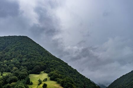 Fog over green forest covered mountains with fog covered valley between themの写真素材