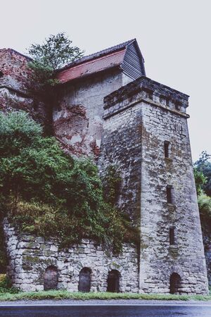 Tree covered old stronghold watchtower ruin in the mountains near a mountain roadの写真素材