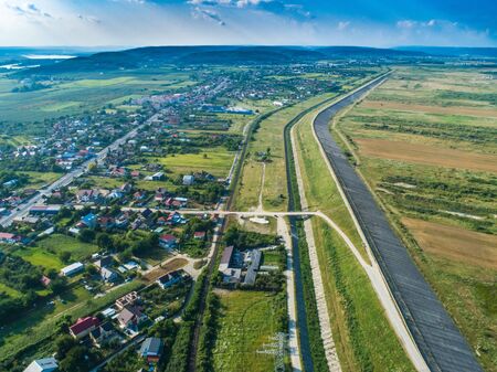 Drone view of dam wall near residential area with forest in the backgroundの写真素材