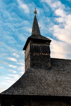Upwards view of the bell tower of an old wooden church on a cloudy blue sunset sky in Maramuresの写真素材