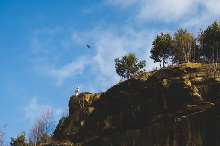 Bird flying over a cross on a mountain rockの写真素材