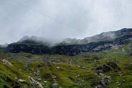 Fog and clouds hitting mountain peakの写真素材